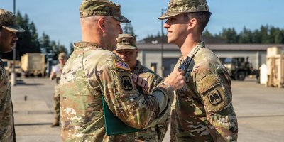 Lt. Col. Kellan Travis, commander of Joint Base Lewis McChord's 2nd Battalion, 158th Aviation Regiment, 16th Combat Aviation Brigade (left), pins an Army Achievement Medal on Pfc. Ian Tate, of the same unit, on July 13 for his work assisting a stranded motorist near JBLM on June 12. (U.S. Army photo by Sgt. Taylor Zacherl)