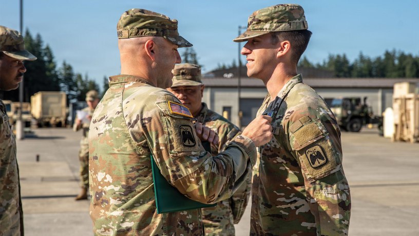 Lt. Col. Kellan Travis, commander of Joint Base Lewis McChord's 2nd Battalion, 158th Aviation Regiment, 16th Combat Aviation Brigade (left), pins an Army Achievement Medal on Pfc. Ian Tate, of the same unit, on July 13 for his work assisting a stranded motorist near JBLM on June 12. (U.S. Army photo by Sgt. Taylor Zacherl)