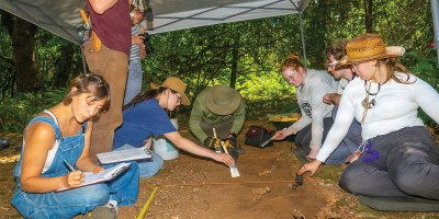 Oregon State University Archaeology Field School students document a test unit as Andrew Pauly, standing, a graduate teaching assistant, photographs the excavation at Najaf Training Center, Ore., July 14, 2026.
