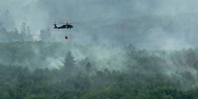 A U.S. Army National Guard UH-60 Black Hawk helicopter assigned to the 34th Combat Aviation Brigade transports water in a Bambi Bucket over wildfires in Northern Minnesota, July 15, 2026.
