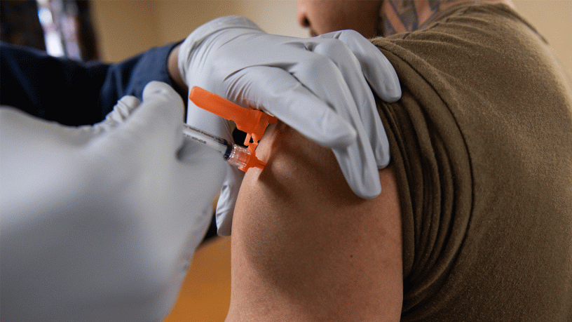 Logistics Specialist Seaman Frenys Hechavarria, from West Palm Beach, Florida, is administered an influenza vaccination by Hospital Corpsman 2nd Class Adam Collins, from Chicago, on a barge assigned to USS Ronald Reagan (CVN 76) at Naval Base Kitsap in Bremerton, Washington, Oct. 21, 2025.