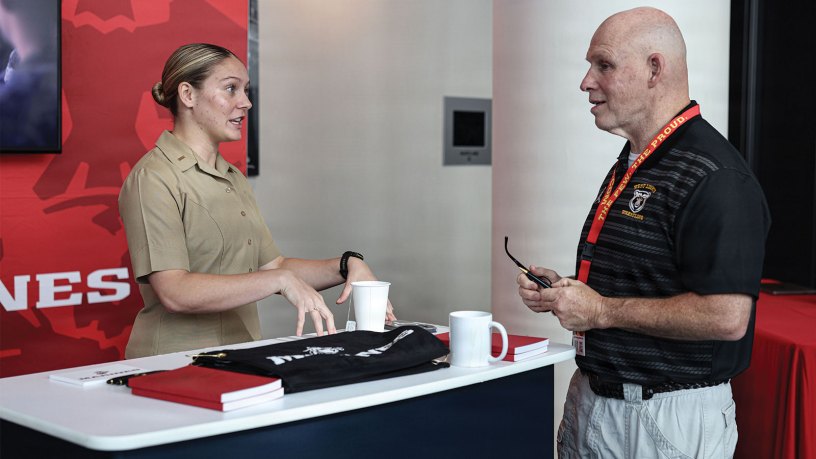 U.S. Marine Corps 2nd Lt. Bailee Mumaw, a student awaiting The Basic School, left, speaks to Troy Bell, head women’s wrestling coach at West Liberty University during the National Wrestling Coaches Association Convention on July 31, 2026, in Baltimore.