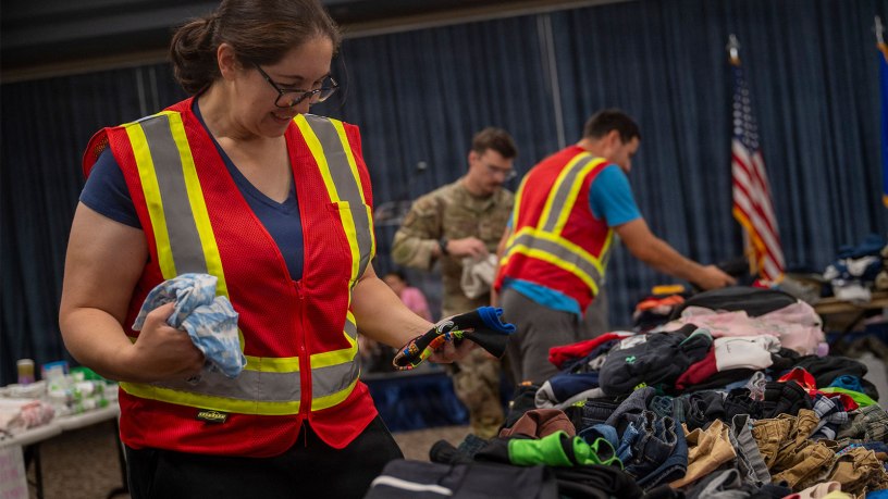 A volunteer for an Emergency Family Assistance Center folds donated clothes on Fairchild Air Force Base, Washington, August 2, 2026. The Fairchild Military Family and Readiness Center activated the EFAC to provide support to military families who were impacted by wildfires across the region through donations and assistance resources. (U.S. Air Force photo by Staff Sgt. Emily Farnsworth)