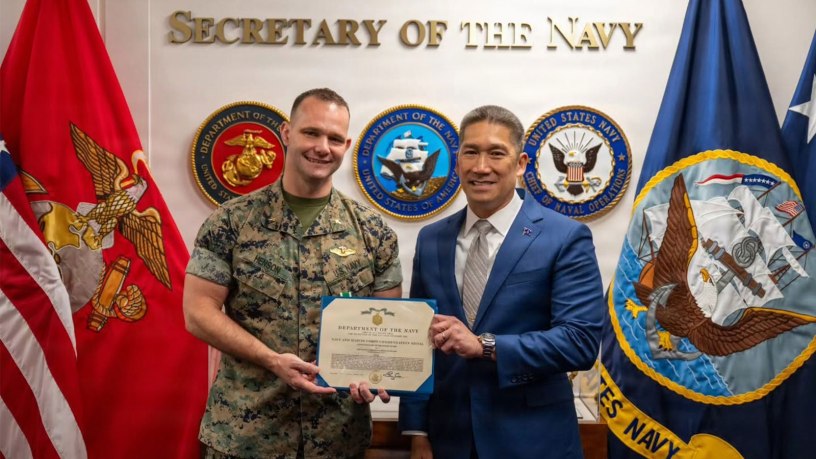 Acting Secretary of the Navy Hung Cao presents Chaplain Derek M. Henson, Headquarters Marine Corps Religious Operations Officer, Office of the Chaplain of the Marine Corps, with the Navy and Marine Corps Commendation Medal during a ceremony at the Pentagon in Arlington, Virginia, Aug. 4, 2026.