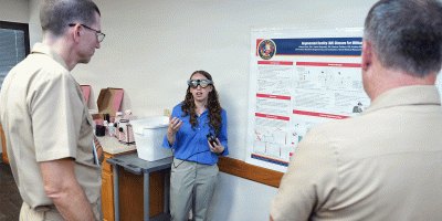 Alissa Klein, of Agoura Hills, Calif., an intern assigned to Naval Medical Research Unit (NAMRU) San Antonio, presented research on augmented reality glasses for military medics to Cmdr. Nicholas Hamlin, executive officer and Lt. Cmdr. Cameron Burnett, director, Directed Energy Health Affects, at the Battlefield Health and Trauma Research Institute.