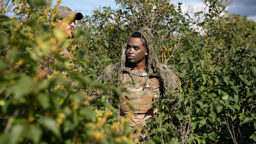 U.S. Army Spc. Shakim Shuler, assigned to Headquarters and Headquarters Company, 2nd Battalion, 37th Armored Regiment, NATO Forward Land Forces Battle Group–Poland, listens to feedback during the concealment and target acquisition exercise from a British soldier from Finder Troop of the Light Dragoons at the Bemowo Piskie Training Area, Poland, Aug. 20, 2026.