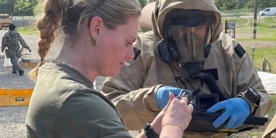 Dr. Emma Sarles conducts maintenance on a camera for a member of a site assessment team during an exercise.