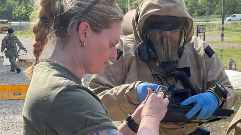 Dr. Emma Sarles conducts maintenance on a camera for a member of a site assessment team during an exercise.