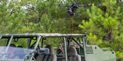 A tethered unmanned aerial system (Te-UAS) hovers behind an Infantry Squad Vehicle-Utility (ISV-U) during a Maneuver Battle Lab (MBL) assessment at McKenna Field Landing Site on Fort Benning, Ga., Aug. 6, 2026.