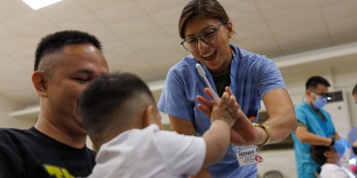 U.S. Navy Petty Officer 3rd Class Honey Diaz, a dental corpsman assigned to 1st Dental Battalion, 1st Marine Logistics Group, encourages a child during Exercise Koa Moana 2026 in Koror, Palau, Aug. 7, 2026.