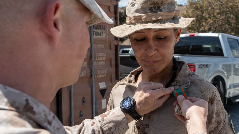 U.S. Navy Petty Officer 3rd Class Valeria Carmona, a hospital corpsman, with the 1st Battalion, 6th Marine Regiment, 2nd Marine Division, receives a Navy and Marine Corps Achievement Medal from Lt. Col. Keegan Kinkade the battalion commander of the 1st Battalion, 7th Marine Regiment, 1st Marine Division, both assigned to Joint Task Force-Southern Border (JTF-SB) in support of Operation Ardent Vanguard, during an award ceremony near Campo, California, Aug. 15, 2026.