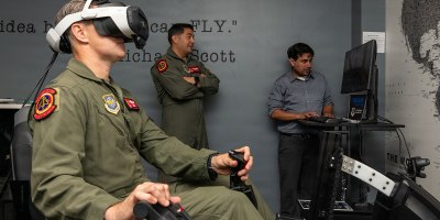 U.S. Air Force Col. Brian Thomasson, left, 60th Operations Group commander, operates the Experiential Air Refueling Lightweight simulator while Lt. Col. Ed Silva, 21st Airlift Squadron commander, and a Specular Theory staff member observe from a separate screen at Travis Air Force Base, California, Aug. 18, 2026.