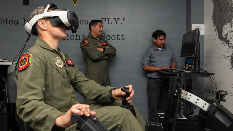 U.S. Air Force Col. Brian Thomasson, left, 60th Operations Group commander, operates the Experiential Air Refueling Lightweight simulator while Lt. Col. Ed Silva, 21st Airlift Squadron commander, and a Specular Theory staff member observe from a separate screen at Travis Air Force Base, California, Aug. 18, 2026.