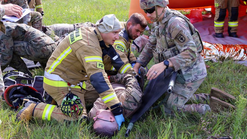 Polish military firefighters and U.S. Army medics from the 928th Medical Company, Area Support, treat the simulated injuries of a U.S. Soldier assigned to the 1st Infantry Division, roleplaying as a plane crash survivor during a joint U.S.-Polish (USPOL) mass casualty exercise, Sept. 2, 2026 in Powidz, Poland.
