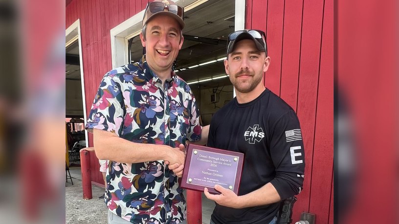 Denali Borough Mayor Chris Noel, left, congratulates Staff Sgt. Nathaniel Grimes, chief of the Anderson Volunteer Fire Department, after presenting him with the 2026 Denali Borough Mayor’s Community Service Award during the Anderson Strawberry Festival in Anderson, Alaska, July 11, 2026.