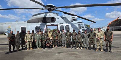 U.S. Air Force and Tanzania People’s Defence Force personnel pose beside a Tanzanian military helicopter during an aerial patient movement knowledge exchange at the 603rd Air Transport Station.